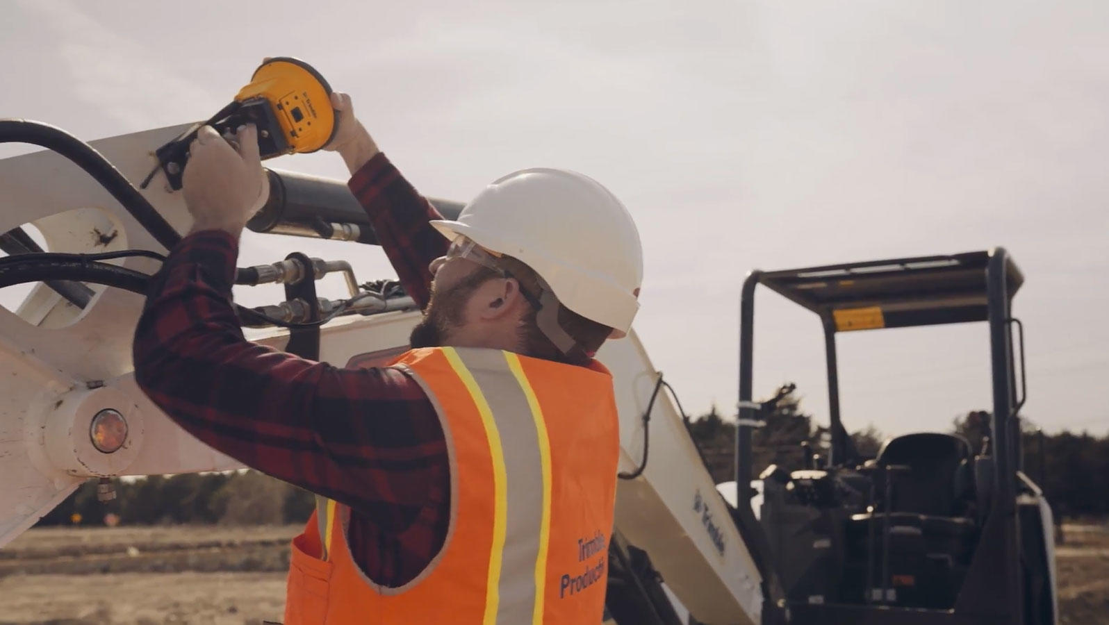 Man attaching antenna onto excavator